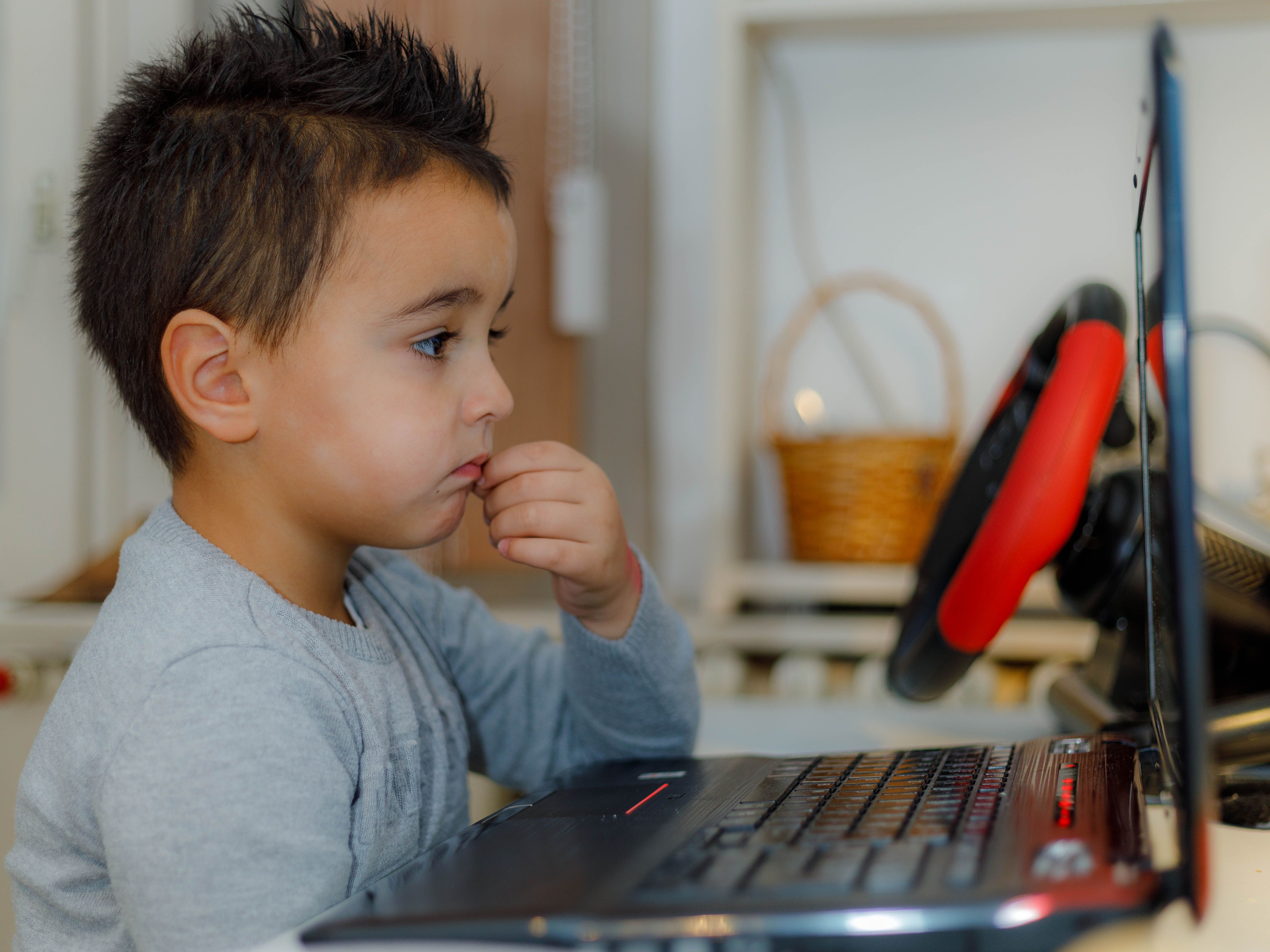 Child practising Python on a laptop with a guidebook